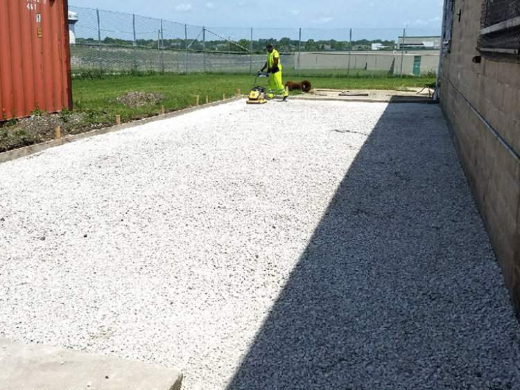 A man compacs gravel to prepare for new concrete